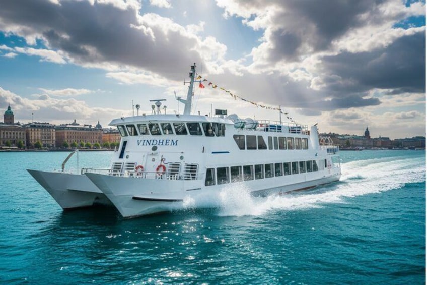 A white cruise ship named VINDHEM sailing on a body of water with a cityscape in the background. 1