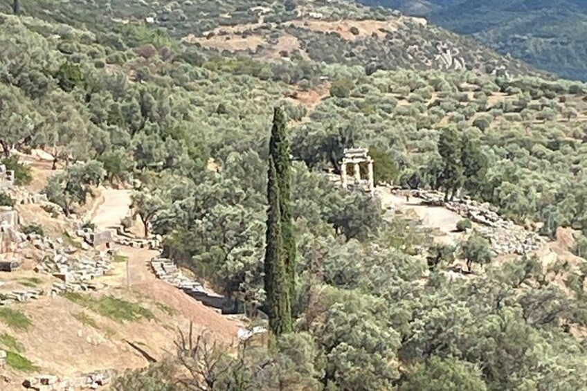 A mountainous landscape with ancient ruins, a prominent tall column, and a temple structure. 5