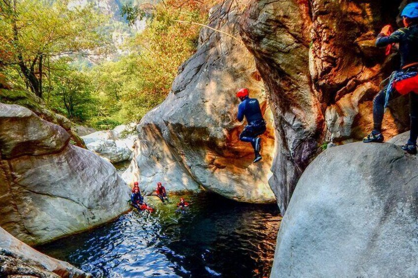 People rappelling down a rocky cliff into a river. 1