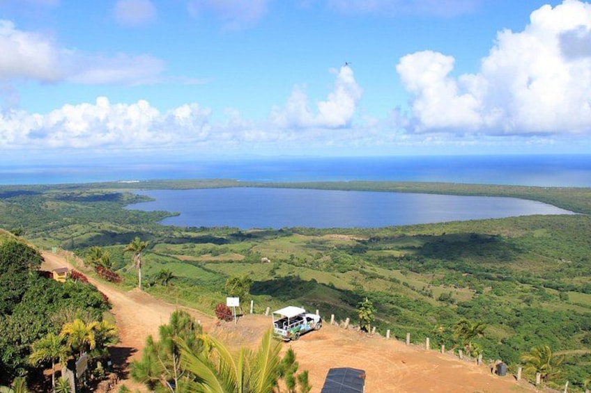 A coastal landscape with a dirt road, a parked vehicle, and a body of water in the distance. 2