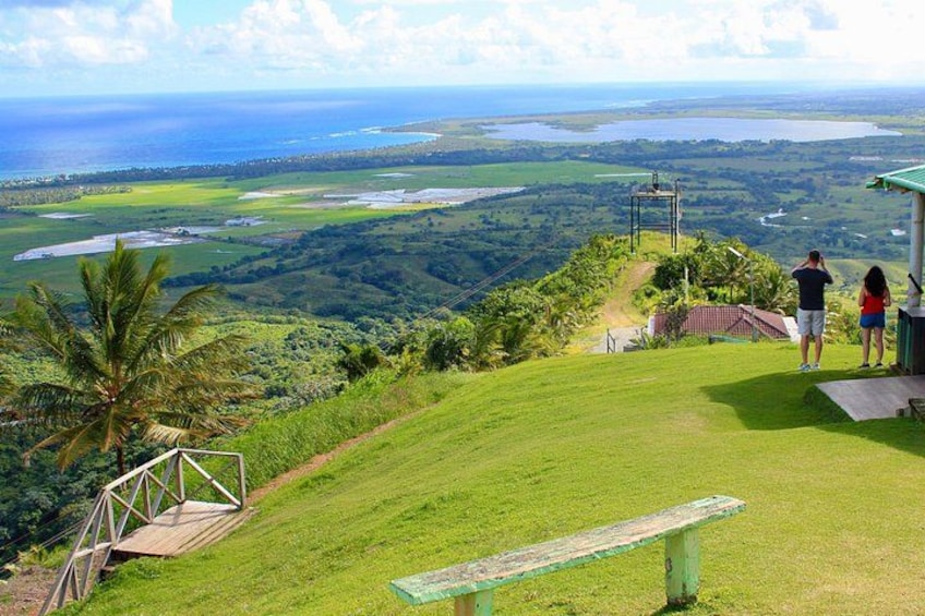 A grassy hill with a bench, a wooden structure, and a view of the ocean and landscape. 3