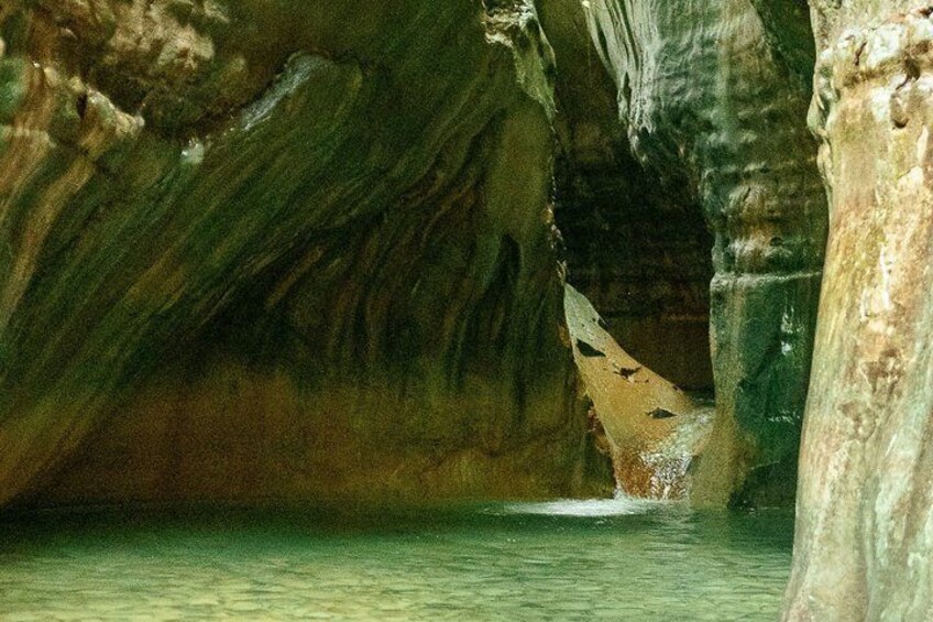 Una cueva con estalactitas y estalagmitas, agua en el fondo y una gran formación rocosa. 2