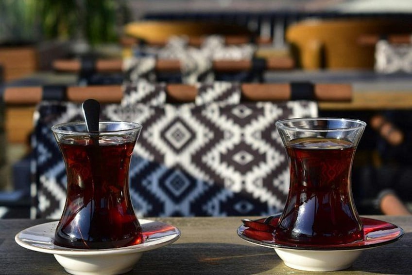 Two glasses of tea on saucers, a patterned cushion, and a wooden table. 5