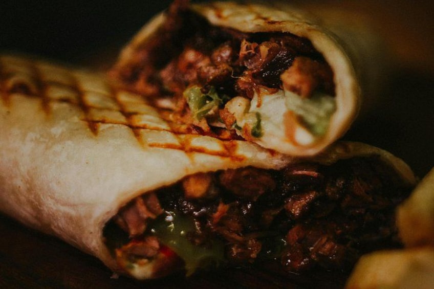 A burrito with visible fillings and a sauce drizzle. 1