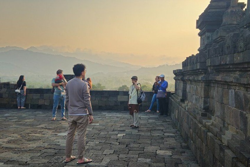 Un groupe de personnes se tient sur une plateforme en pierre, d’où elles dominent un paysage montagneux. 4