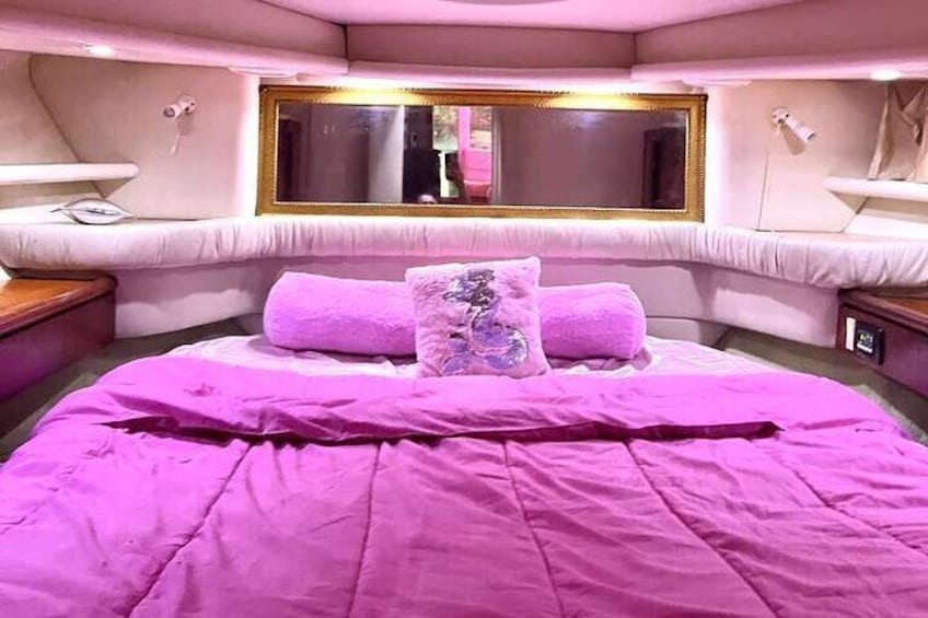 A pink-themed bedroom with a bed, pillows, a mirror, and bedside tables. 3