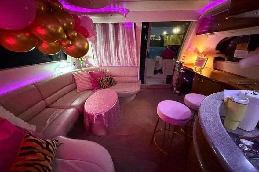 A pink-themed interior with a sofa, round tables, and balloons. 3