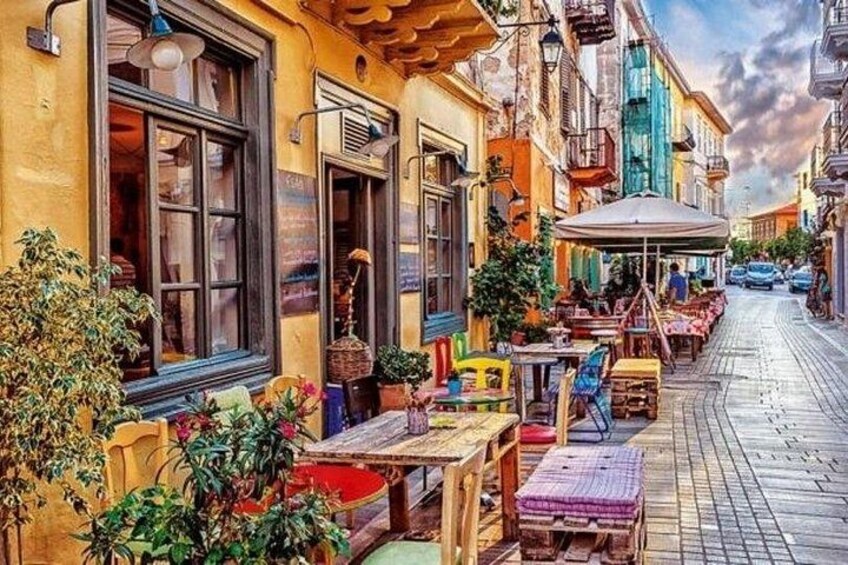 A colorful street with outdoor seating, potted plants, and a cobblestone path. 5
