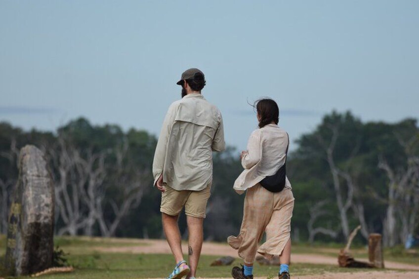 Two people walking on a path in a natural setting with trees and a clear sky. 3
