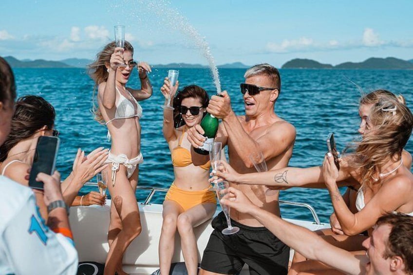 A group of people on a boat, some wearing swimsuits, toasting with champagne glasses. 3