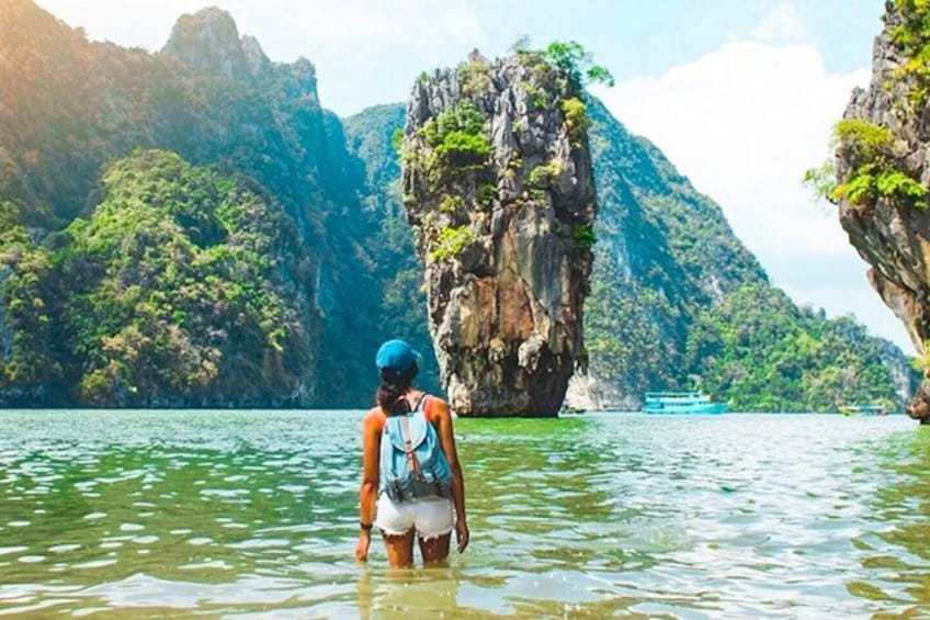 A person standing in water with a mountainous landscape in the background. 2