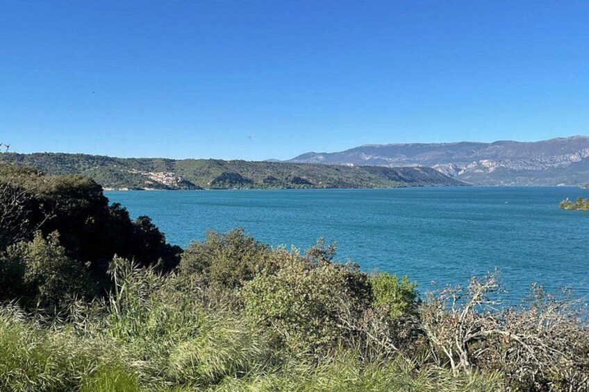 A lake with clear blue water, surrounded by hills and vegetation. 5