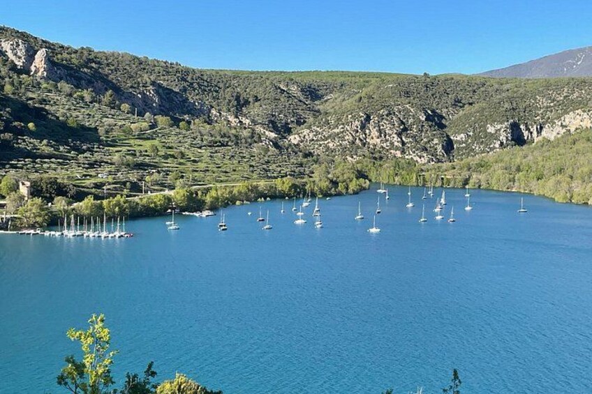 A lake with sailboats, surrounded by hills and greenery. 4