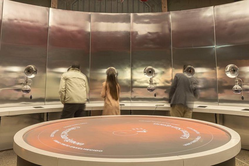 A metallic wall with circular mirrors and a circular platform with inscriptions. 4