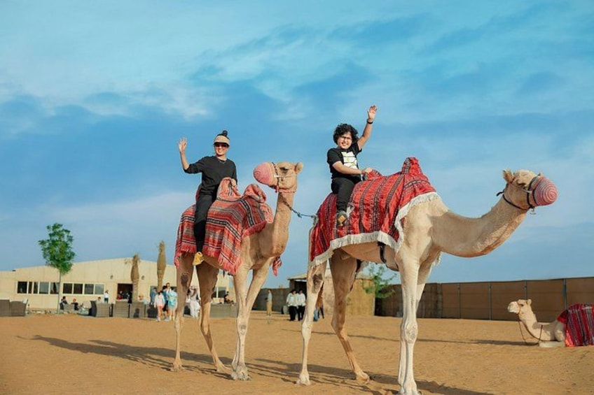Two camels with riders in a desert setting. 3