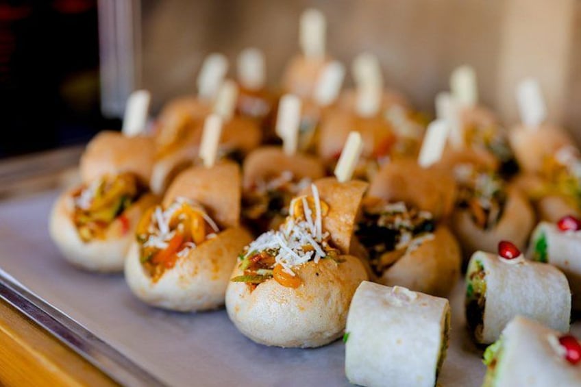 A tray of food items, possibly appetizers, with some garnished with cheese and others with a red garnish. 4
