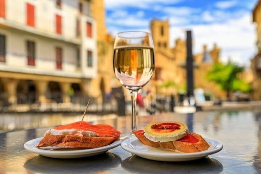 Two plates of food and a glass of white wine on a table with a view of a canal and buildings in the background. 4