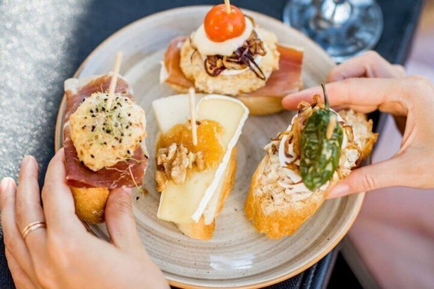 A plate with various food items, including bread with toppings and a cherry tomato. 2