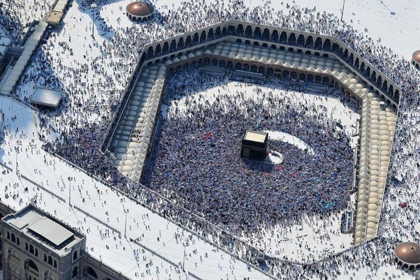 A large crowd gathered around a central structure in a square with a surrounding wall and domed buildings. 2