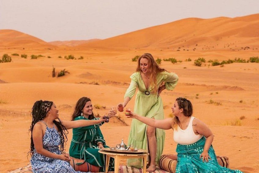 A group of people in a desert setting, with sand dunes in the background. 1