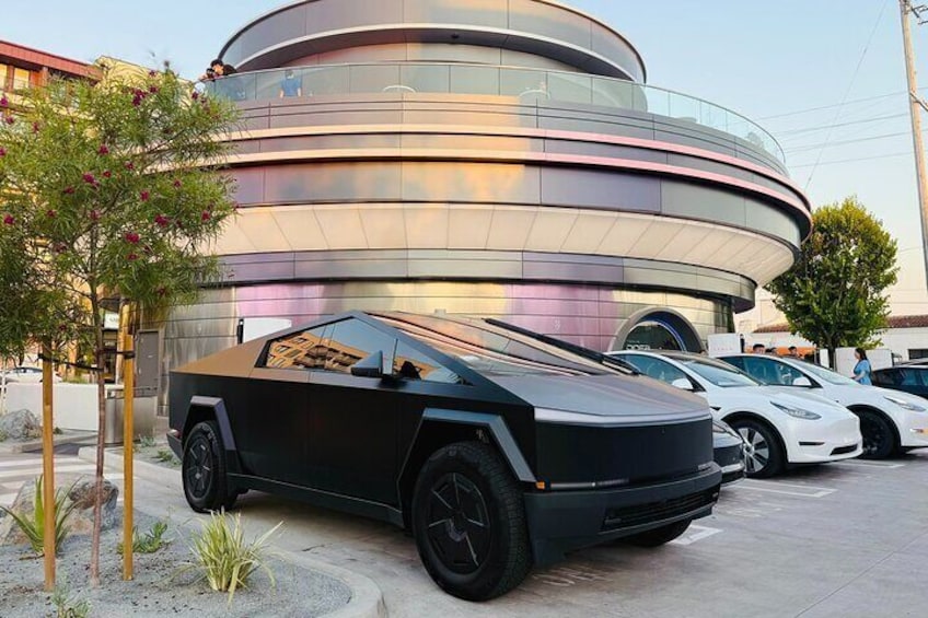A futuristic black car parked in front of a modern building with a circular design. 4