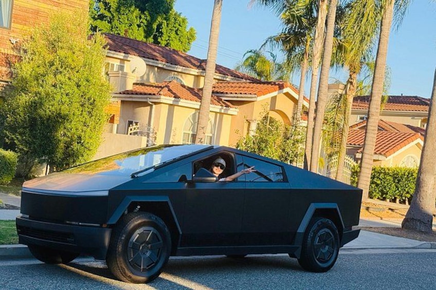 Et futuristisk køretøj parkeret på en villavej med palmer og huse i baggrunden. 3