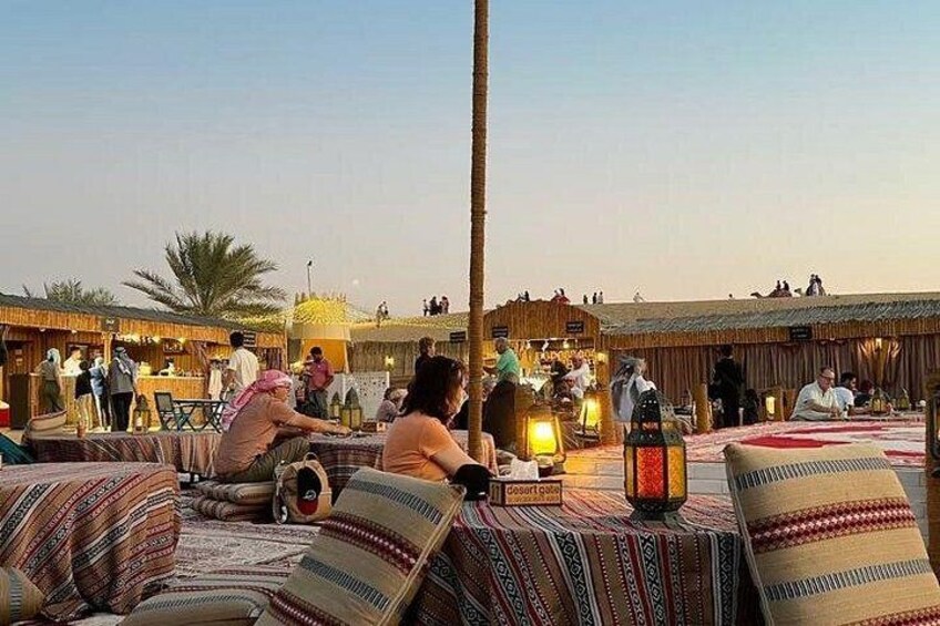 A traditional outdoor seating area with patterned cushions and a central table, surrounded by palm trees and a clear sky. 4