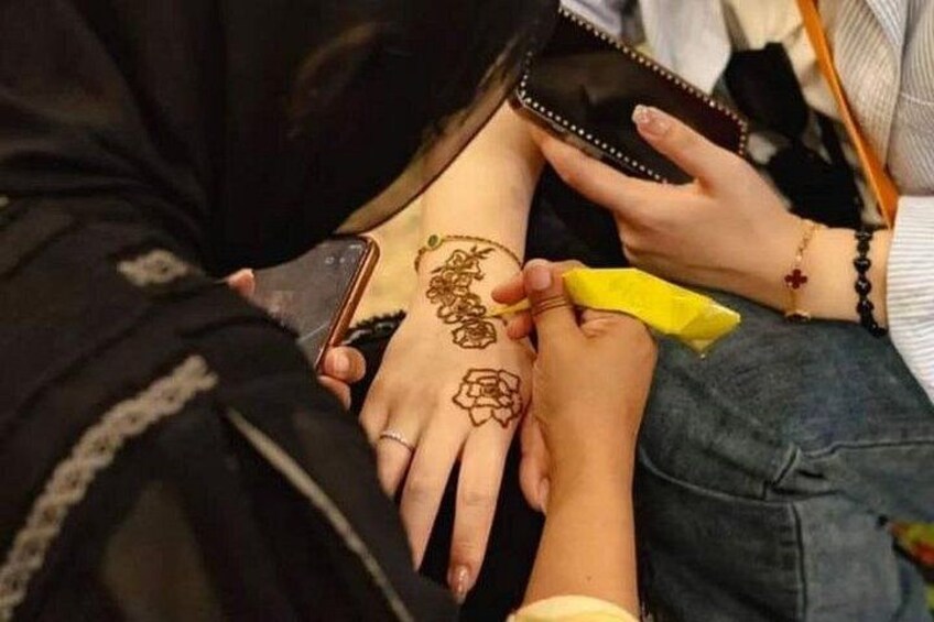 A person applying henna on another person's hand. 3