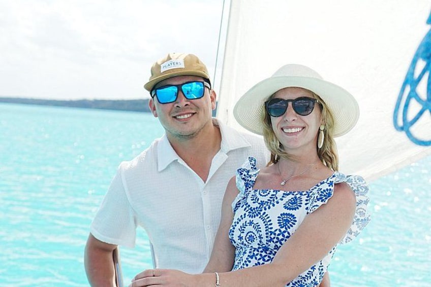 A person wearing a white shirt and a hat, standing on a boat with a blue ocean in the background. 3