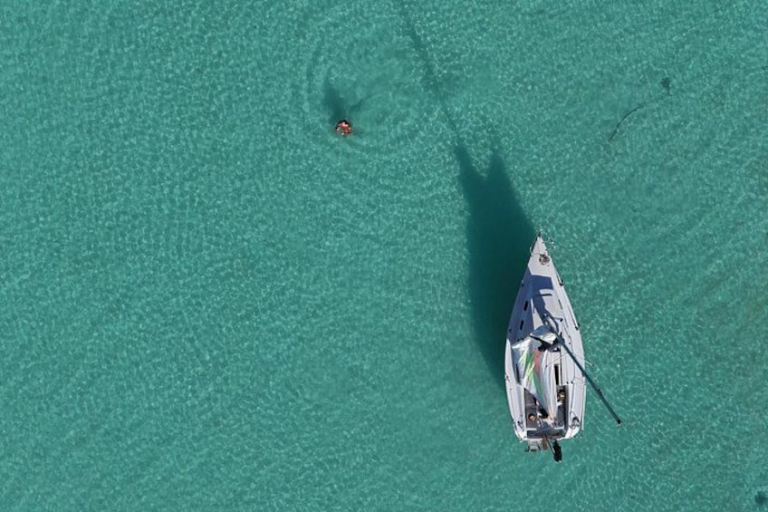A small boat on turquoise water with a shadow of a person. 2