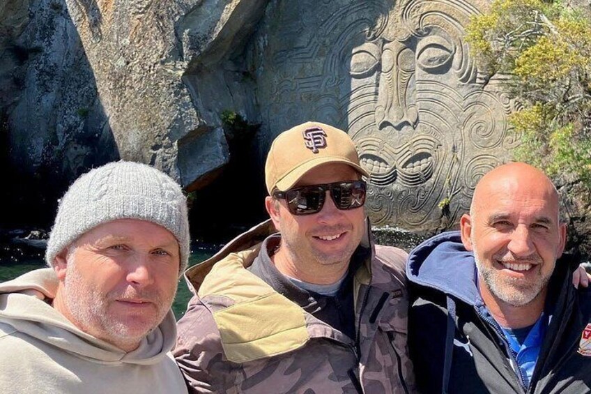 Three people in front of a carved stone face. 2