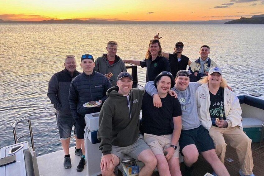 A group of people on a boat with a sunset in the background. 3