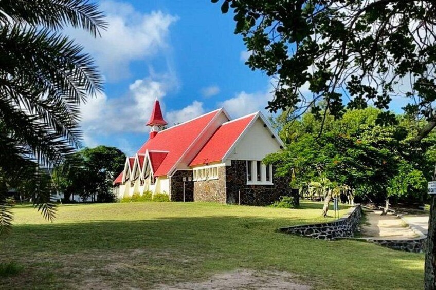 A church with a red roof and white walls, surrounded by a grassy area and trees. 3