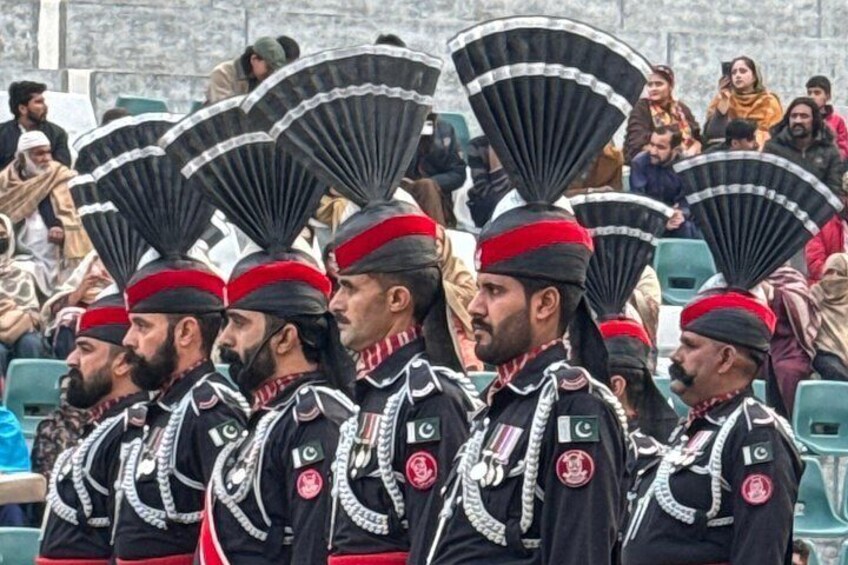 A group of uniformed individuals in ceremonial attire with fans, standing in a line. 5
