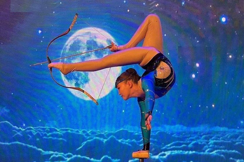 A person performing an acrobatic stunt with a bow and arrow against a backdrop of a moon and stars. 2