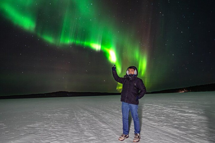 A person standing on a snowy surface with the aurora borealis in the background. 5