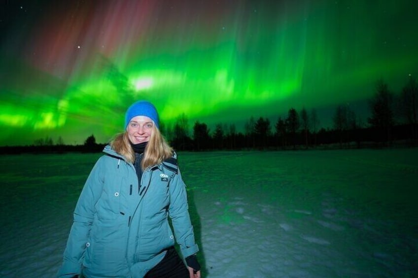 Una persona sobre suelo cubierto de nieve bajo un cielo nocturno con auroras boreales verdes. 1