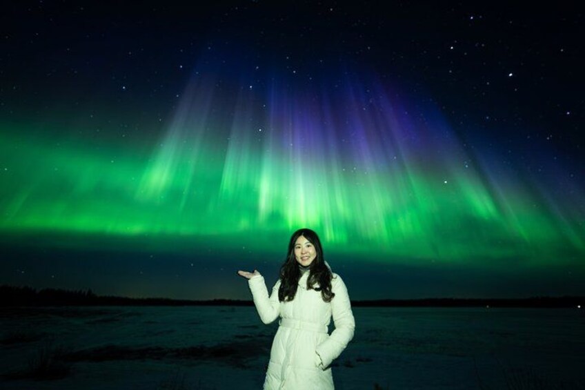 A person standing in a snowy landscape under a night sky with the aurora borealis. 1