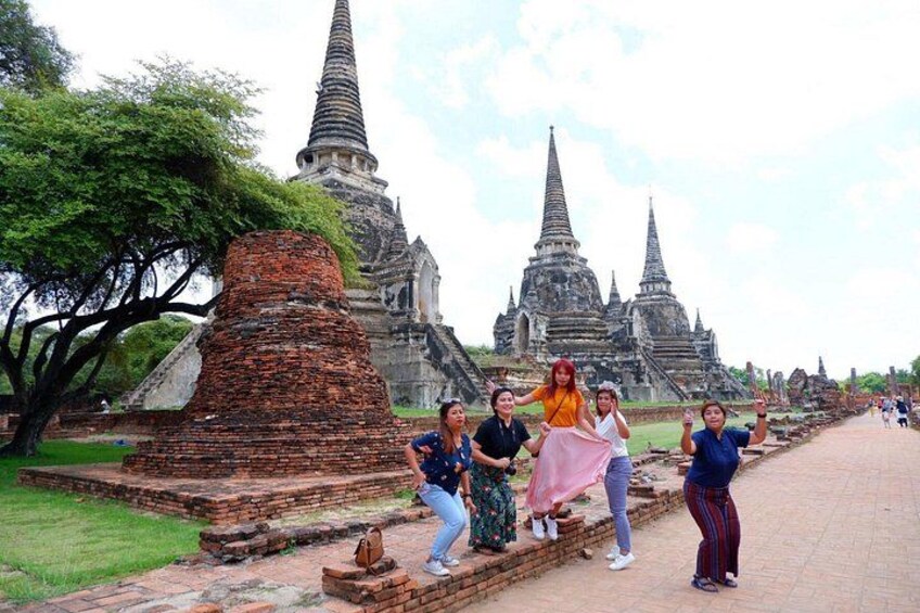 Eine Gruppe von Personen posiert vor alten Tempelruinen mit einer großen Ziegel-Stupa und mehreren Spitzentürmen. 3