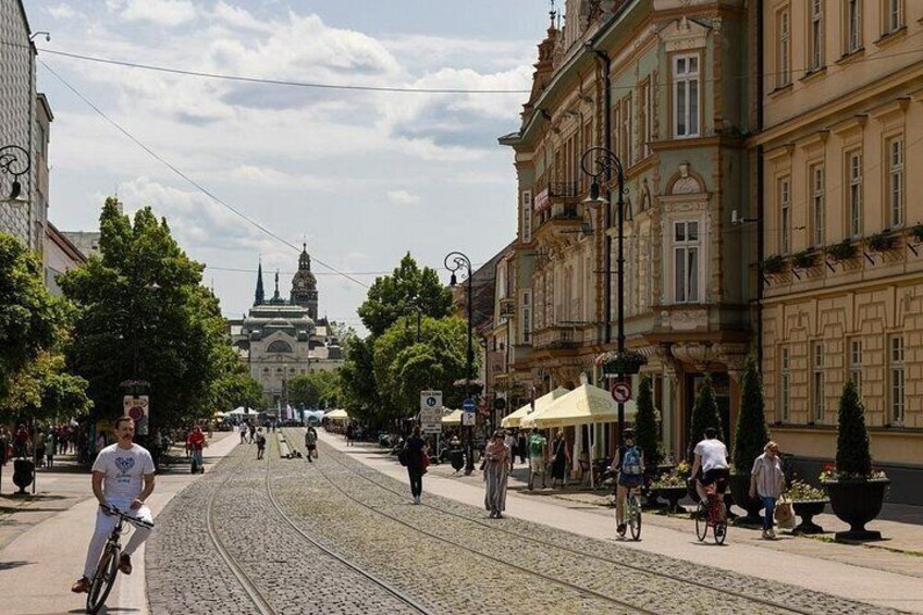 A cobblestone street with a tram, pedestrians, and historic buildings. 2