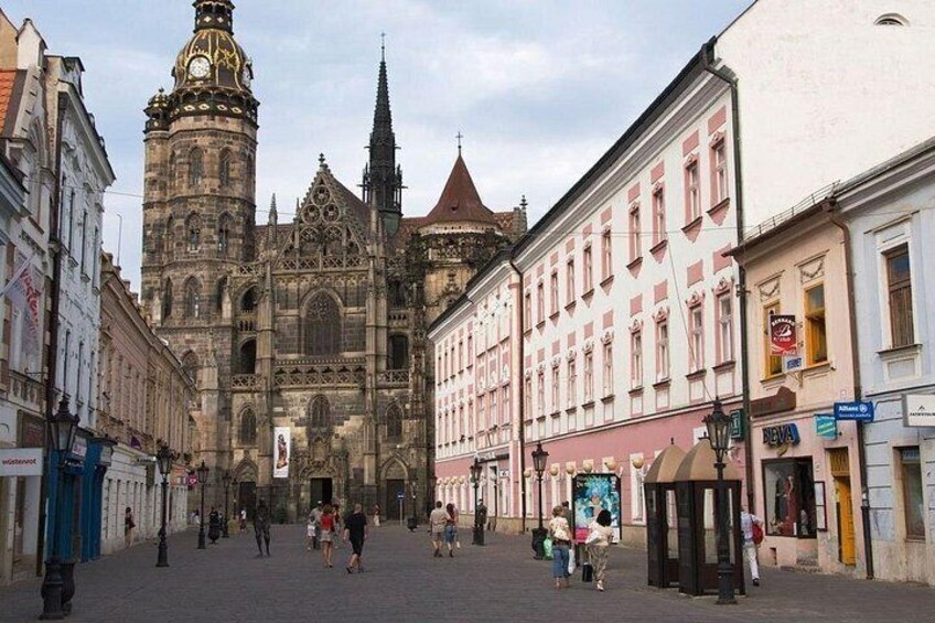 A historic cathedral with a clock tower, surrounded by traditional buildings and a cobblestone street. 4