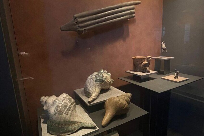En museiutställning med antika föremål, bland annat keramik, en skulptur och ett verktyg av sten. 4