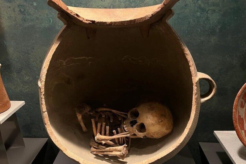En stor keramikurna som innehåller ett mänskligt kranium och ett skelett. 2