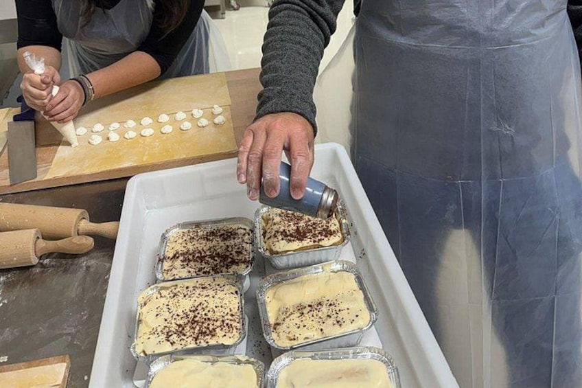 A person preparing desserts, with trays of food and a rolling pin on the counter. 2