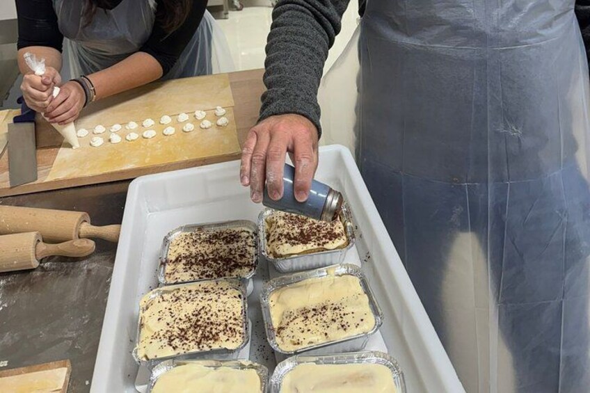 A person preparing desserts, with trays of baked goods and a rolling pin on the counter. 5