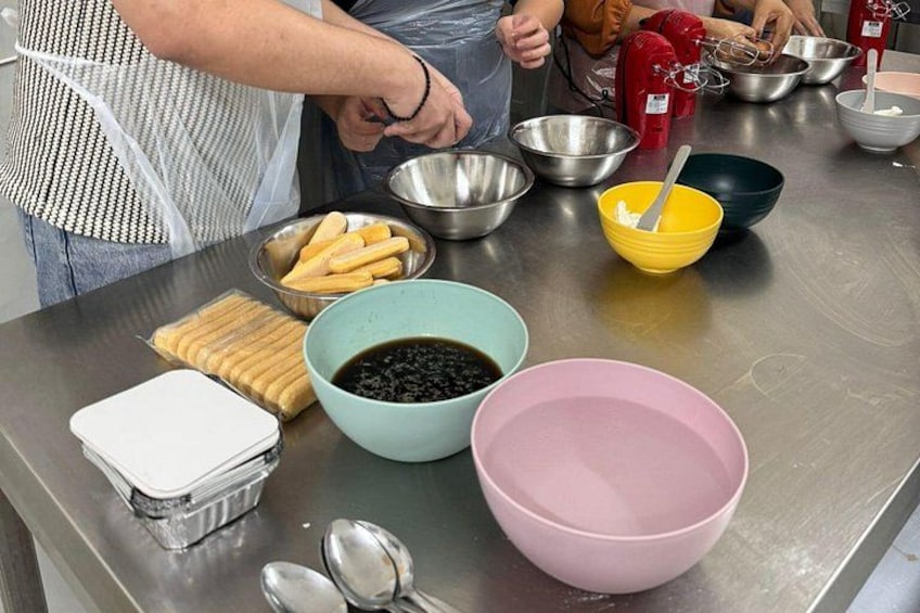 Una cucina con diverse ciotole contenenti ingredienti, una frusta e una persona che prepara cibo. 5