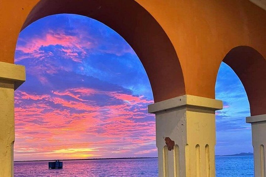 Ein Sonnenuntergang über dem Meer, eingefasst von einer Struktur mit Bögen. 2