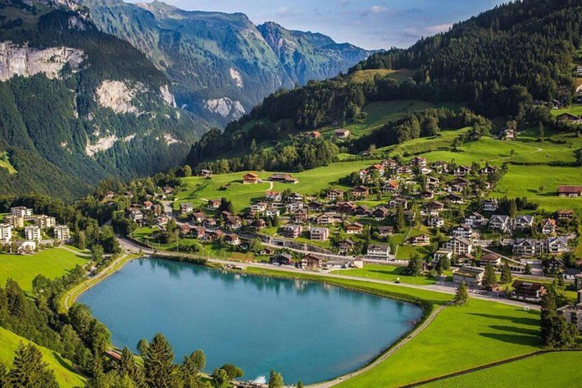 A lakeside village with houses, a lake, and mountains in the background. 5