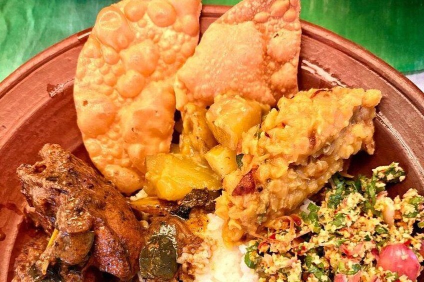 A traditional clay pot filled with various dishes including fried food, a leg of meat, and a side of greens. 3