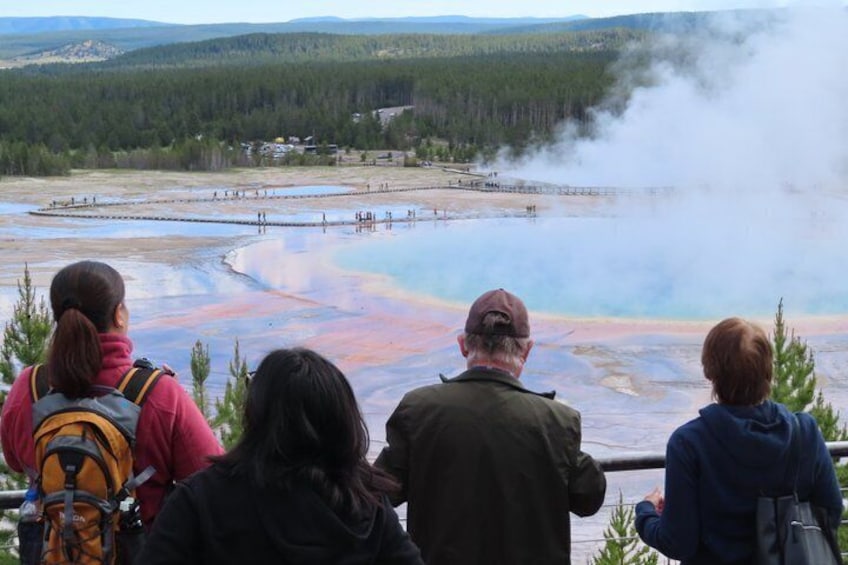 A group of people observing a geothermal area with colorful mineral deposits and steam. 2
